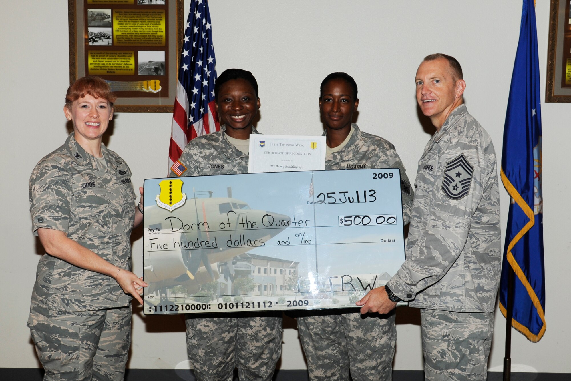 GOODFELLOW AIR FORCE BASE, Texas -- Col. Kimberlee Joos, 17th Training Wing Commander, and Chief Master Sgt. Scott Lumpkin, 17th TRW Command Chief, present the 17th Training Wing Team GAFB Student Dormitory of the Quarter to B250, Army, during the wing quarterly awards ceremony, July 25. (U.S. Air Force photo by Staff Sgt. Austin Knox)