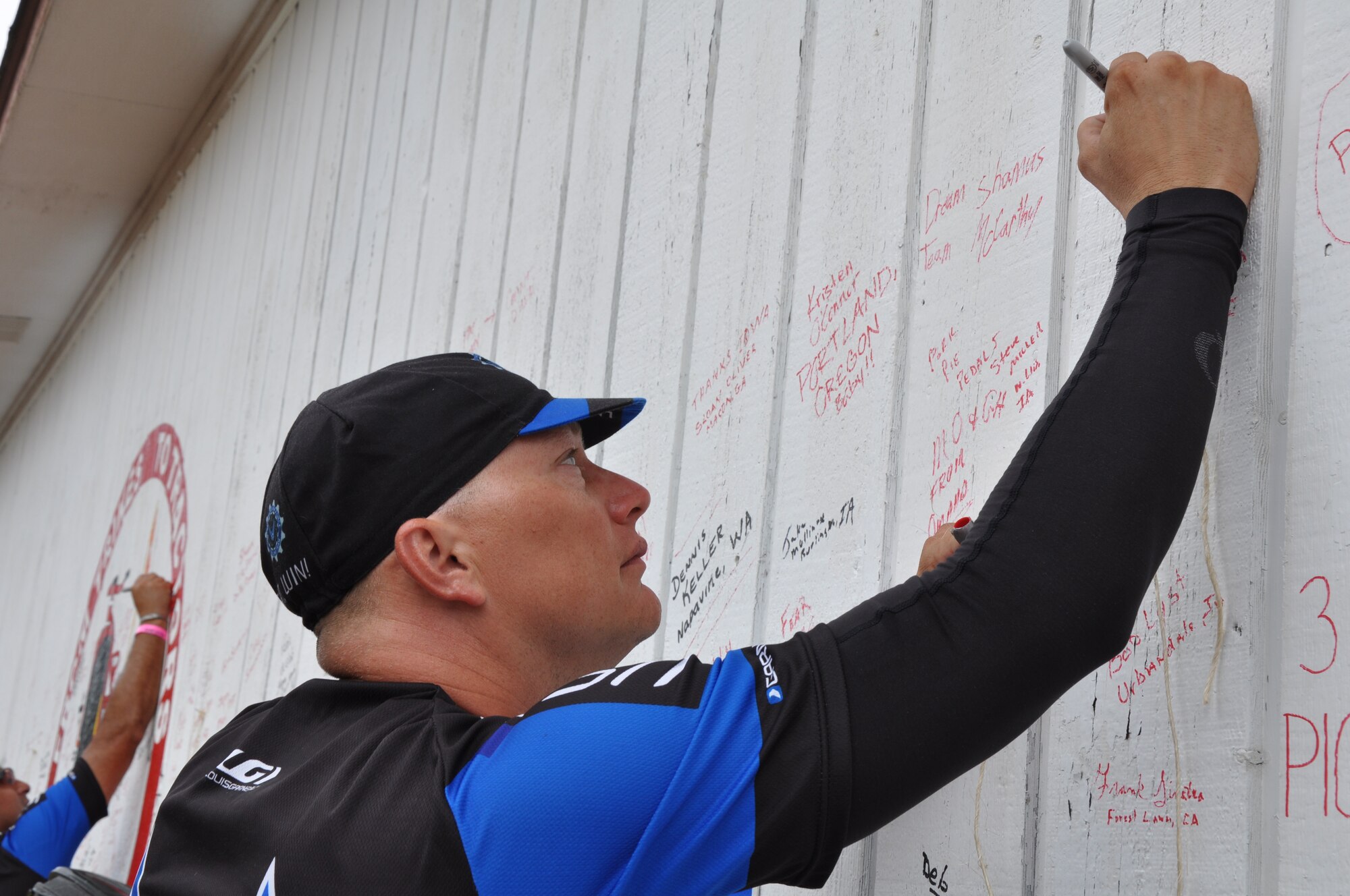 Master Sgt. Jerry Cromer, 301st Medical Squadron surgical technician and Air Force Cycling Team member, signs a wall located at Dallas Center, Iowa.  Signing the wall is a tradition for those who ride through the town during the Register's Annual Great Bicycle Ride Across Iowa. Like most AFCT members, Cromer, whose been a rider for more than 20 years, heard about RAGBRAI through word of mouth.  (U.S. Air Force photo by Staff Sgt. Abigail Klein)

