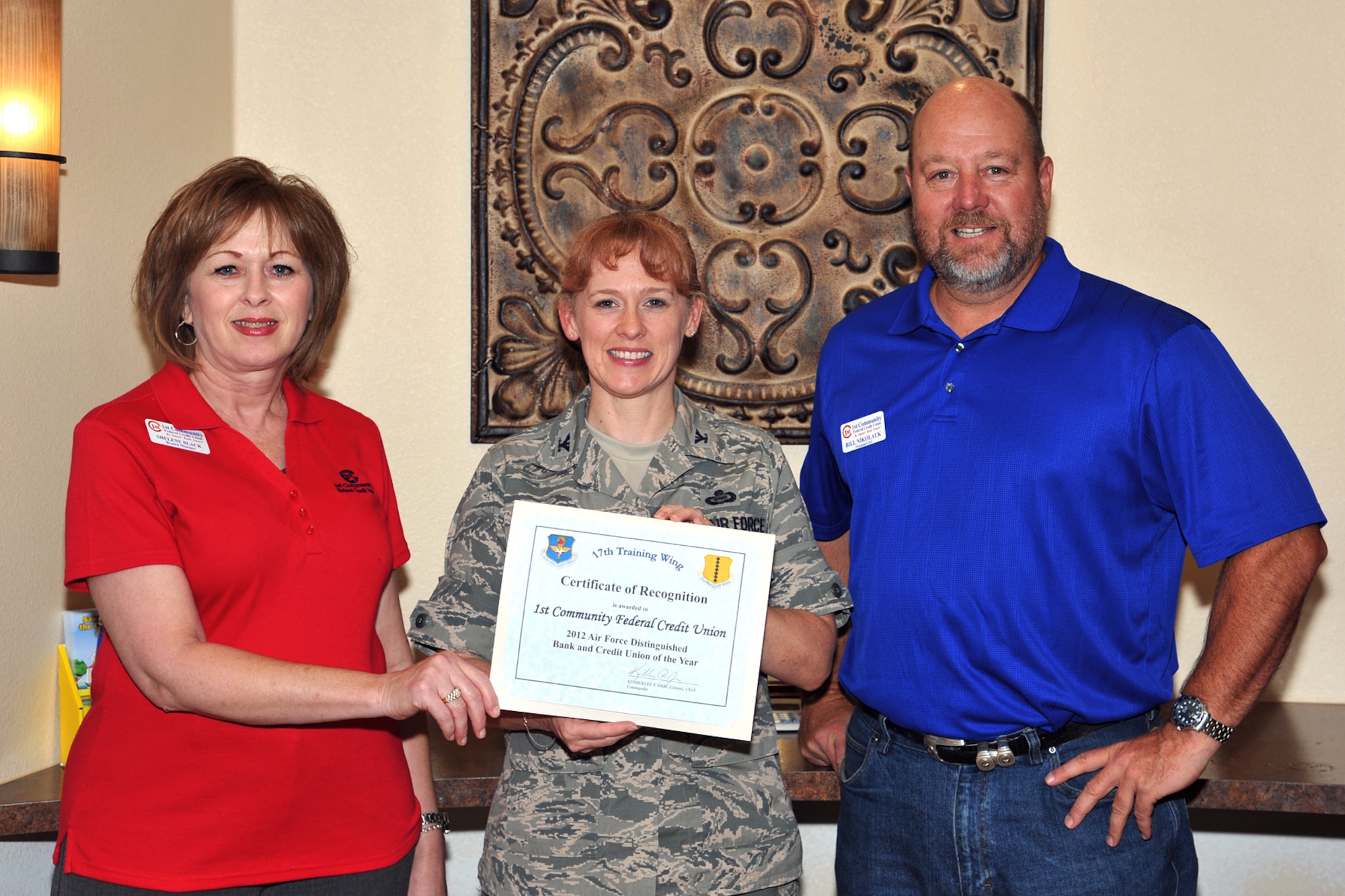 GOODFELLOW AIR FORCE BASE, Texas-- Bill Nikolauk, 1st Community Federal Credit Union president, and Skelene Black, branch manger, accept the 2012 Air Force Distinguished Bank and Credit Union of the Year Award from Col. Kimberlee Joos, 17th Training Wing Commander, July 26. 1st Community Federal Credit Union was selected out of 37 entries to be recognized for its outstanding support provided to Team Goodfellow and the overall Air Force mission.