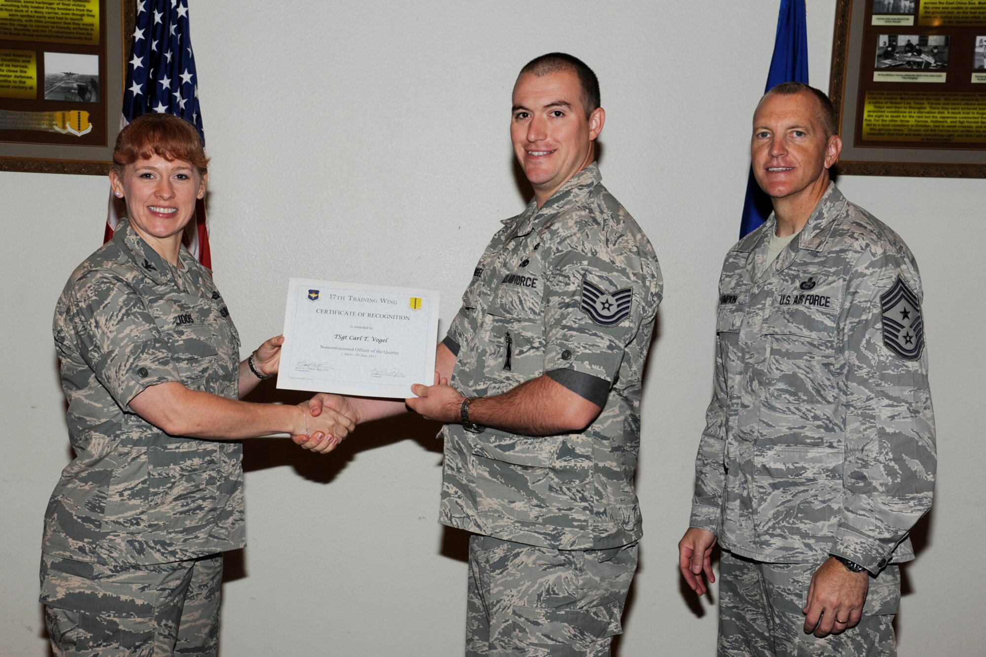 GOODFELLOW AIR FORCE BASE, Texas -- Col. Kimberlee Joos, 17th Training Wing Commander, and Chief Master Sgt. Scott Lumpkin, 17th TRW Command Chief, present the 17th Training Wing NCO of the Quarter to Technical Sgt. Carl Vogel, 17th Training Group, during the wing quarterly awards ceremony, July 25. (U.S. Air Force photo by Staff Sgt. Austin Knox)
