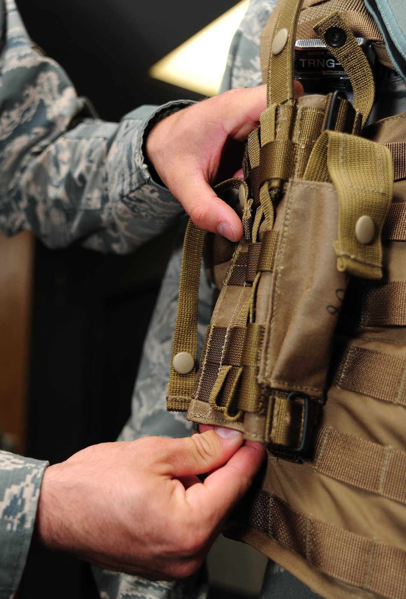 Senior Airman Ethan Mason, 509th Operations Support Squadron aircrew flight equipment journeyman, readjusts the location of an M9 holster on an Airsave vest at Whiteman Air Force Base, Mo., July 16, 2013. Pilots carry M9 as a first line of defense against insurgents, terrorists and other potential threats on the ground. (U.S. Air Force photo by Staff Sgt. Nick Wilson/Released) 