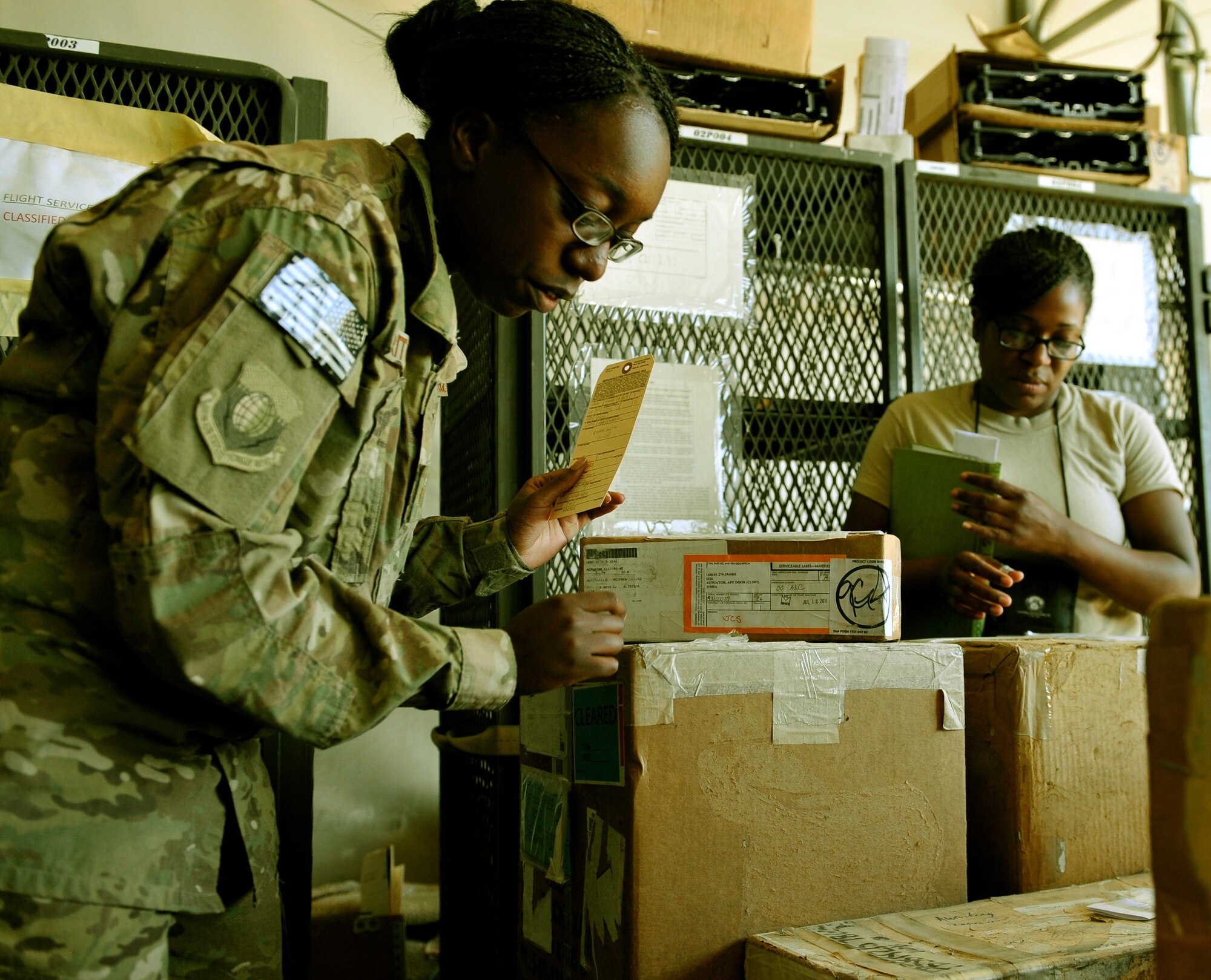 (left to right) Staff Sgt. Sabrina Pritchett, 455 Expeditionary Logistics Readiness Squadron flight service center technician and Staff Sgt. Latoya Jenkins, ELRS C-130 maintenance supply liaison, look for an ordered C-130 aircraft part in the aircraft parts store on Bagram Airfield, Afghanistan May 30, 2013. The facility stores all aircraft parts for C-130’s and other aircraft on the base. Pritchett is deployed from Moody Air Force, Ga., and Jenkins from Little Rock AFB, Ariz. (U.S. Air Force photo/ Staff Sgt. Stephenie Wade)