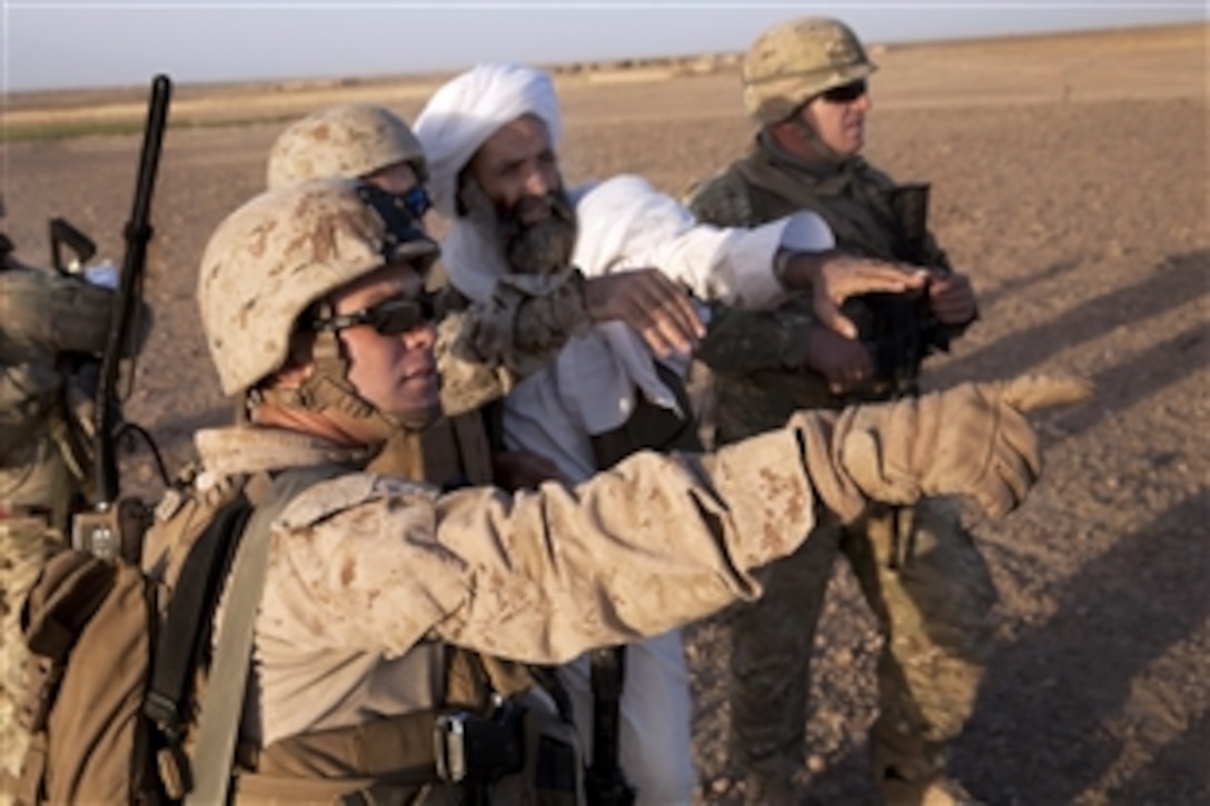 U.S. Marine Corps Staff Sgt. Paul Rogers, left, points at the terrain while talking to an Afghan villager during a patrol in Mohammad Abad village in Afghanistan’s Helmand province, July 23, 2013. Rogers, a team leader, is assigned to Georgian Liaison Team 9. 