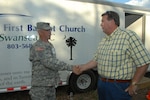 Col. Gordon Johnson, of the S.C. Governor's Counter Drug Task Force, thanks Pasture Terry Wilder, of the Swansea First Baptist Church, Swansea, S.C., for the donation of a portable shower and laundry trailer for use by soldiers and airmen at the forward operating base facility during National Guard exercise Vigilant Guard, April 20, in Beaufort, S.C. Vigilant Guard is a three-day National Guard-hosted exercise in Beaufort County, beginning April 21. The exercise is designed to better prepare the National Guard for natural disasters in a cooperative effort with various national, state and local government agencies.