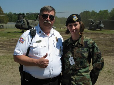 James Colwell, the assistant fire chief for the city of Beaufort, S.C., and his daughter, Airman 1st Class Sarah Colwell of the 75th Security Forces Squadron, Hill Air Force Base, Utah, pose for a picture as two S.C. National Guard CH-47D Chinook helicopters drop off South Carolina Task Force One, urban search and rescue technicians, to support the National Guard's Vigilant Guard exercise taking place April 21 in Beaufort, S.C. The Vigilant Guard exercise here in S.C. involves 3,000 Guard members from across the country and hundreds of personnel throughout the host county of Beaufort, S.C., the S.C. Emergency Management Division and other military, government and non-government organizations.