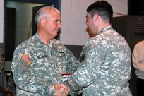 Maj. Gen. Abner C. Blalock, the adjutant general of the Alabama National Guard, hands Maj. Lee Thompson, commander of the 166th Engineer Company, a state flag to fly proudly while deployed in Afghanistan. The 166th left for Camp Atterbury, Ind., on March 2 for a quick training period before deploying to Afghanistan. The 166th Engineer Company's mission is to help construct base camp facilities, help maintain existing facilities, and help the Afghan people improve their infrastructure.
