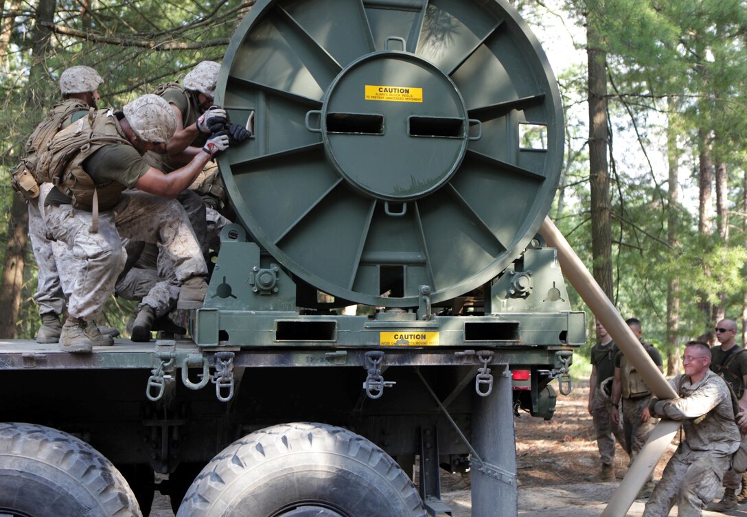 Marines with Bulk Fuel Company B, 6th Engineer Support Battalion, set up a hose reel system during a training exercise here, July 17. Bulk fuel Marines rely on the system to transport fuel from one amphibious assault fuel system to another. Much of the work required Marines to rely on group strength as opposed to machines to assemble the amphibious assault fuel systems. 