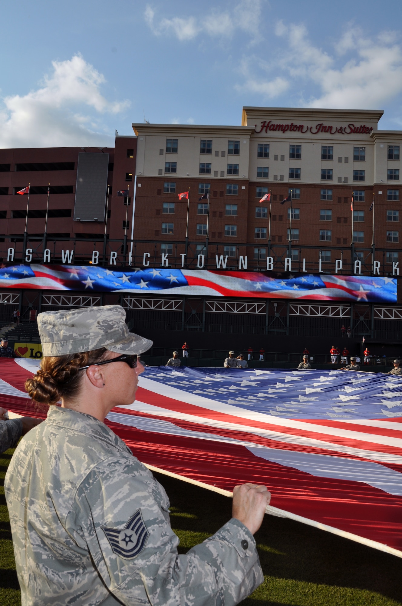 Technical Sgt. Dawn Hardwick, 513th Maintenance Squadron along with 50 other members of Team Tinker, hold a huge U.S. flag during the national anthem at the opening of the Oklahoma City RedHawks military appreciation game on July 27.  Sergeant Hardwick was also recognized during the game because she recently returned from a deployment to South West Asia. The Oklahoma City RedHawks minor league baseball origination held its second hometown heroes celebration of the season to recognize local military members and their families. Members of the 72nd Air Base Wing, 507th Air Refueling Wing, 552nd Air Control Wing, U.S. Navy Strategic Communications Wing One and the Air Logistics Center all volunteered to represent the military during the military appreciation game which included an oath of enlistment and special recognition of recently deployed Airmen. (U.S. Air Force Photo/Maj. Jon Quinlan)