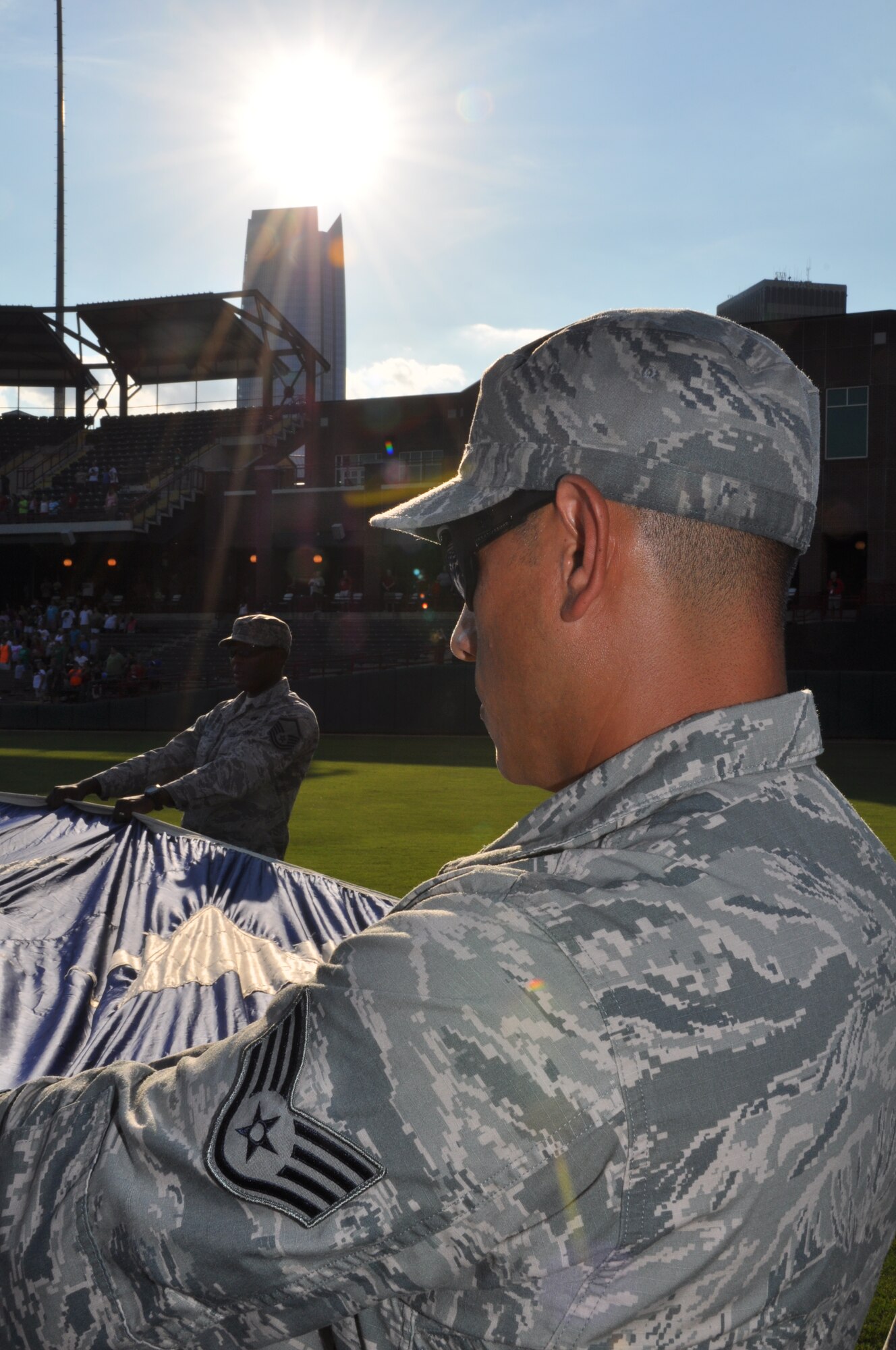 Staff Sgt. Homero Morales-Arellano, 72nd Comptroller Squadron along with 50 other members of Team Tinker, hold a huge U.S. flag during the national anthem at the opening of the Oklahoma City RedHawks military appreciation game on July 27.  Members of the 72nd Air Base Wing, 507th Air Refueling Wing, 552nd Air Control Wing, U.S. Navy Strategic Communications Wing One and the Air Logistics Center all volunteered to represent the military during the military appreciation game which included an oath of enlistment and special recognition of recently deployed Airmen. (U.S. Air Force Photo/Maj. Jon Quinlan)
