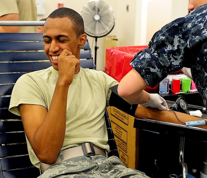 Airman 1st Class Joshua Hernandez, 436th Logistics Readiness Squadron individual protective equipment journeyman,  looks away as a technician sticks a needle in his arm during a military-to-military blood drive July 29, 2013, at Dover Air Force Base, Del. Team Dover collected 71 units of blood to send to service members in deployed areas. (U.S. Air Force photo/Airman 1st Class Ashlin Federick)