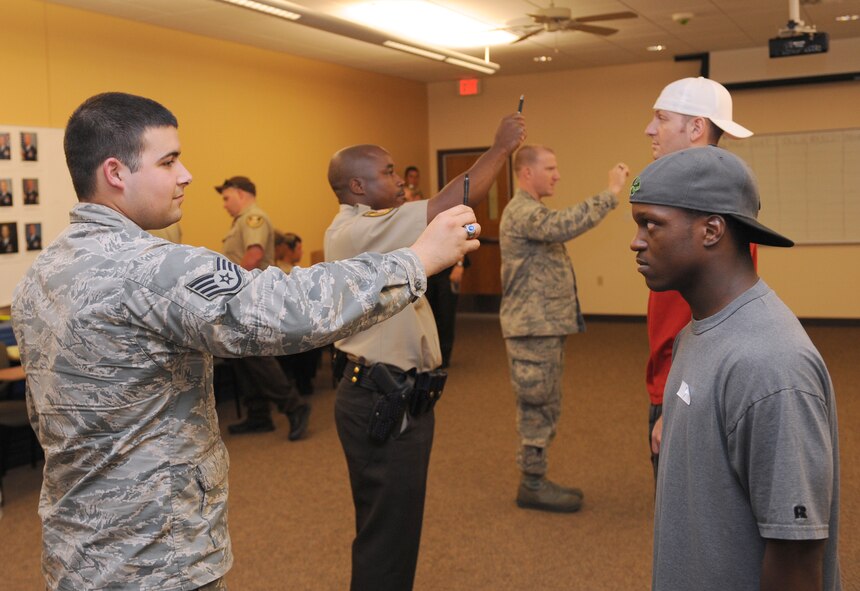 Law enforcement patrolmen perform the horizontal line test on volunteers during standardized field sobriety test training on Barksdale Air Force Base, La., July 24, 2013. The Airmen conducted horizontal line test, nine-step walk and turn and the one-legged stand test. (U.S. Air Force photo/Airman 1st Class Benjamin Gonsier)