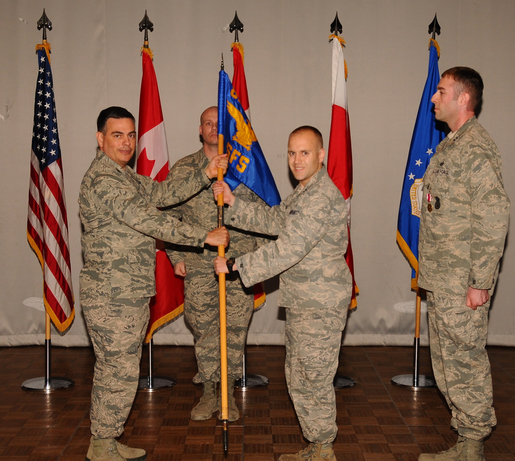 THULE AIR BASE, Greenland – Col. Mike Colón (left), former 821st Air Base Group commander, passes the 821st Security Forces Squadron guidon to Capt. Jason Stack, during a change of command ceremony. Stack took command of the 821st SFS June 13. The 821st SFS is one of the 21st Space Wing’s 23 geographically separated units, and supports Thule’s missile warning, missile defense, space surveillance and satellite command and control missions by managing the integrated defense and force protection of 600 year-round residents and $2.6 billion in resources. Stack replaced outgoing commander Capt. Lucas Hall. (U.S. Air Force photo)