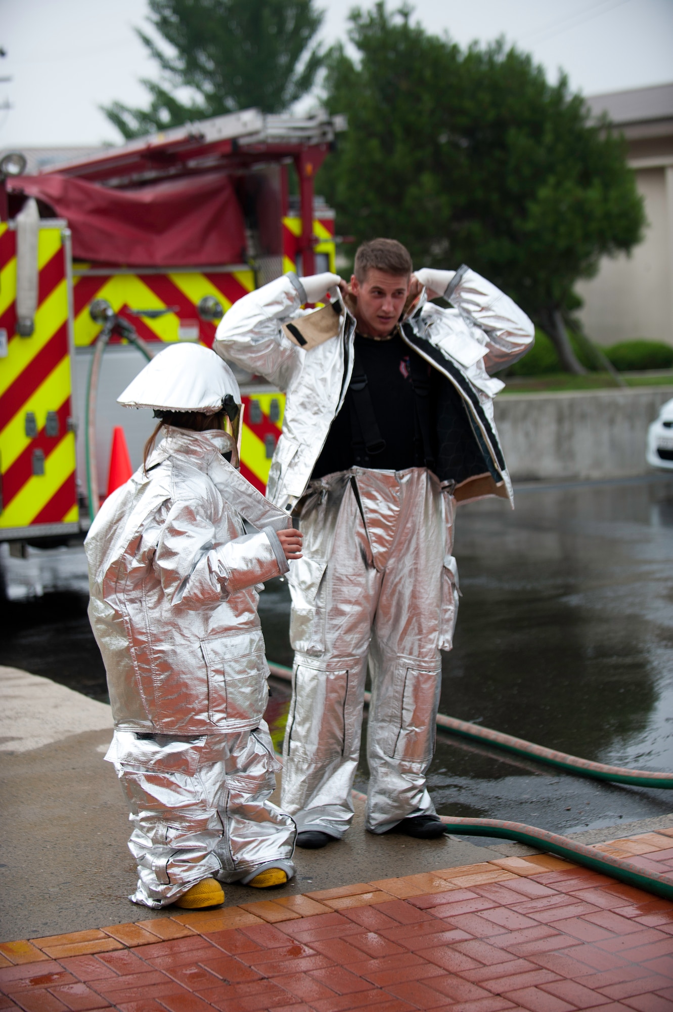 Staff Sgt. Jonathan Fackler, 8th Civil Engineer Squadron, dons a fire proximity suit with a child from the Ilmagwon Orphanage during Summer Fun Day, at Kunsan Air Base, Republic of Korea, July 27, 2013. The child was one of more than 60 who were invited by the Airmen Committed to Excellence Council and gave children from the orphanage a chance to have fun with members of the Wolf Pack. (U.S. Air Force photo by Senior Airman Clayton Lenhardt/Released)