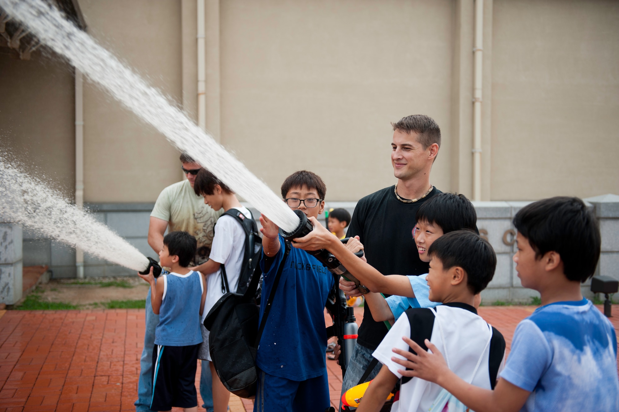 Staff Sgt. Jonathan Fackler, 8th Civil Engineer Squadron, teaches children from the Ilmagwon Orphanage how to direct a fire hose during Summer Fun Day, at Kunsan Air Base, Republic of Korea, July 27, 2013. The base’s fire department ran the fire hose station as part of a larger event organized by the Airmen Committed to Excellence council. (U.S. Air Force photo by Senior Airman Clayton Lenhardt/Released)