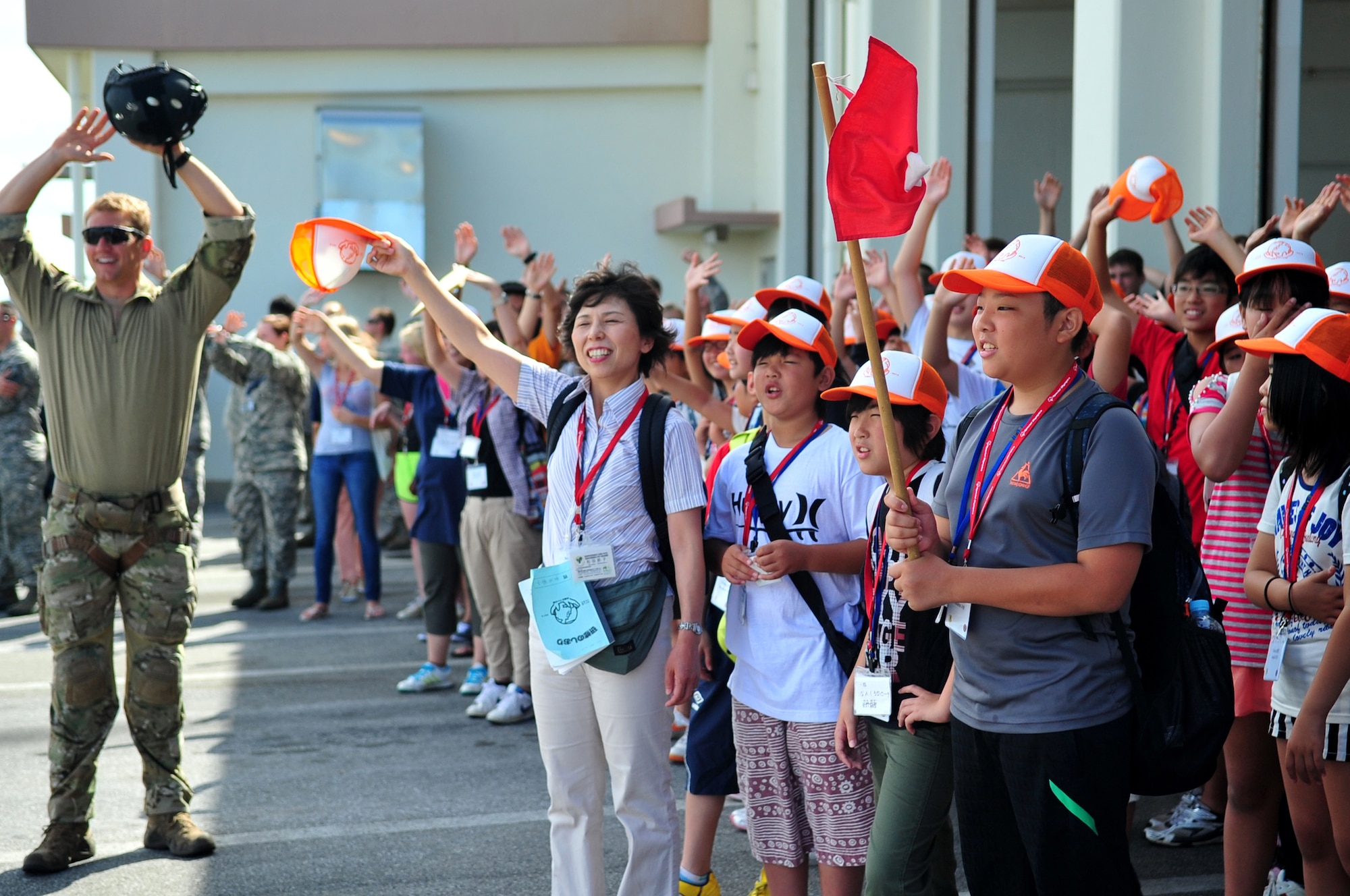 U.S. Air Force Capt. Matthew Arnold, 31st Rescue Squadron combat rescue officer, and Setsuko Wada, Itoi Elementary School principal, encourage sixth-graders from Iitate Village to wave their hands as part of a pararescue demonstration on Kadena Air Base, Japan, July 24, 2013. The pararescue demonstration consisted of a helicopter medical evacuation and was part of a school visit to Kadena that focused on educating the six-graders on military rescue services in an effort to promote peace. (U.S. Air Force photo by Senior Airman E. N. Jacobs/Released)