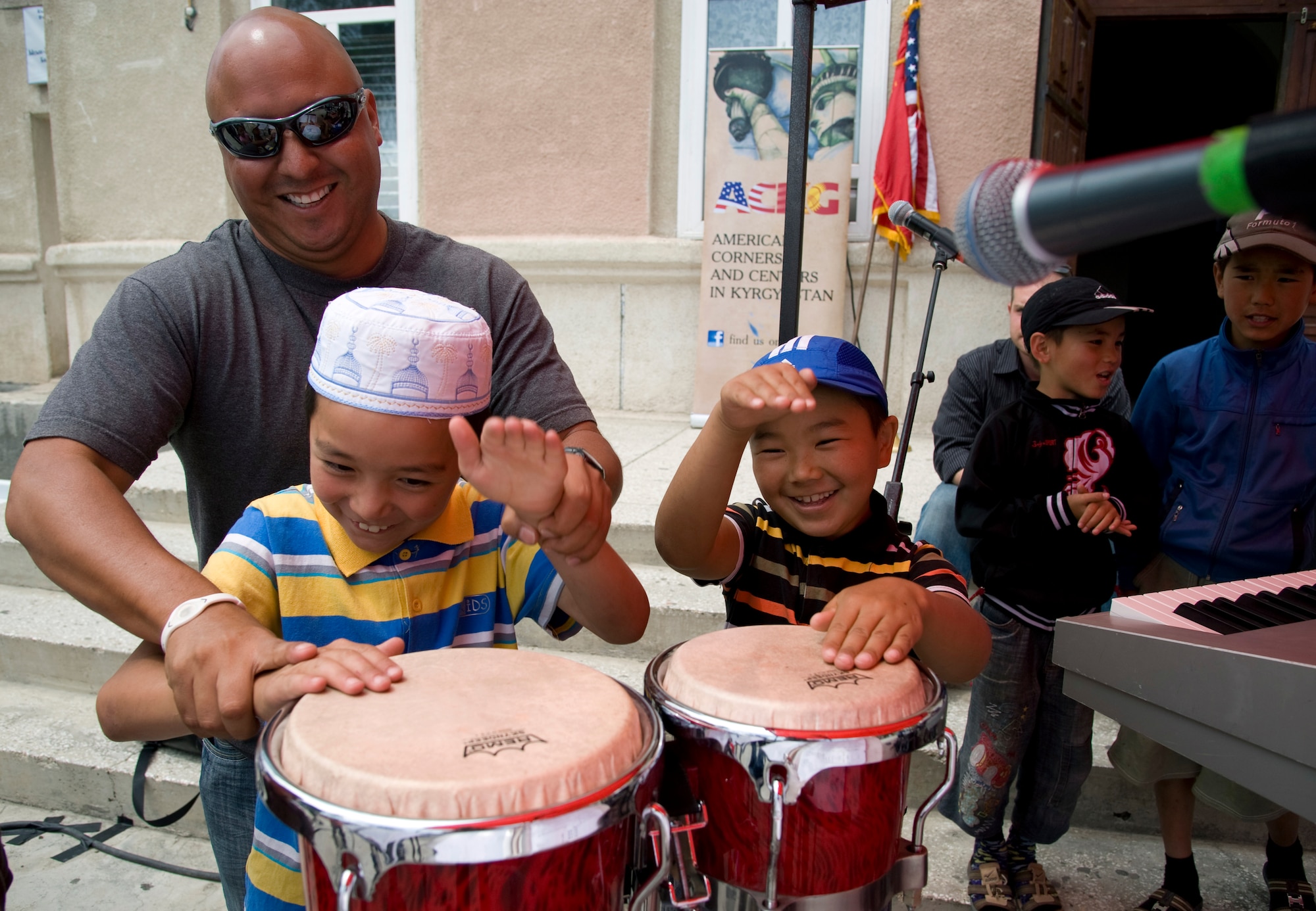 Technical Sgt. Richard Vasquez, U.S. Air Forces Central Command band, Full Spectrum vocalist, teaches local youth how to play percussion in Balykchi City central square, Kyrgyzstan, July 19, 2013. The AFCENT band invited locals of all ages to learn how to play instruments. The concert was part of the AFCENT band’s mission to build international partnerships. (U.S. Air Force photo/Staff Sgt. Krystie Martinez)