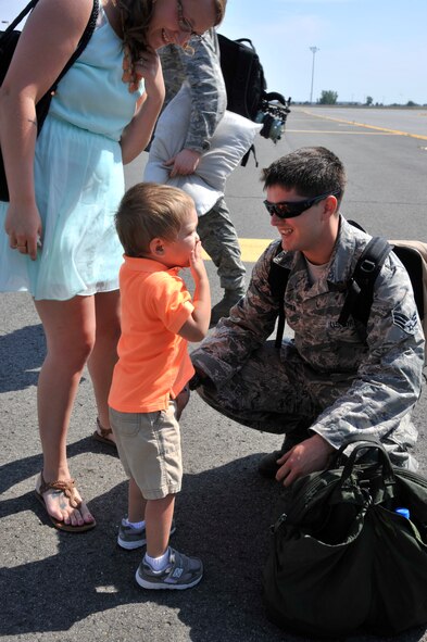 Senior Airman Jacob Pitcher, 92nd Aircraft Maintenance Squadron flying crew chief, is welcomed home by his wife Jill and their son Neyland at Fairchild Air Force Base, Wash., July 30, 2013. Pitcher and several other Airmen were returning from deployments supporting Southwest Asia. (U.S. Air Force photo by Senior Airman Mary O'Dell/Released)
