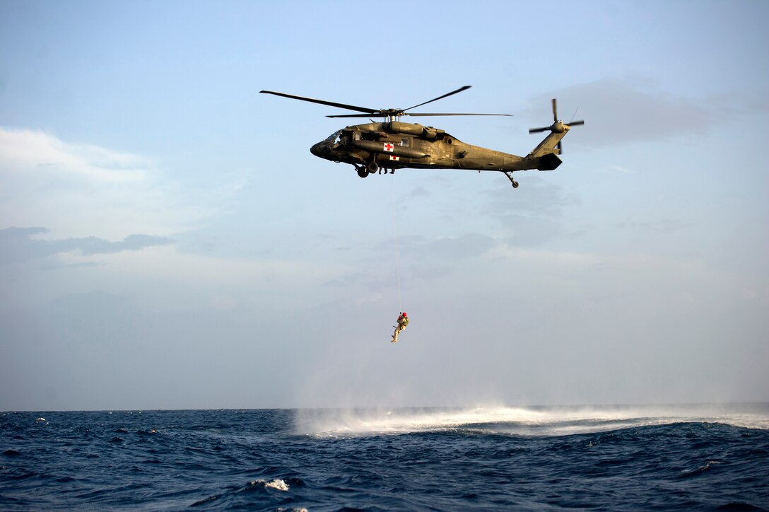 A UH-60 Blackhawk helicopter from 1-228th Aviation Regiment lowers a flight medic into the ocean to conduct hoist operations with Green Berets from 7th Special Forces Group (Airborne) off the coast of Utila, Honduras. July. 25,2013. Two flight crews from 1-228th Aviation Regiment practiced hoist operations by conducting rescue simulations with day and night iterations to stay proficient.(U.S. Army photo by Spc. Steven K. Young/Released)