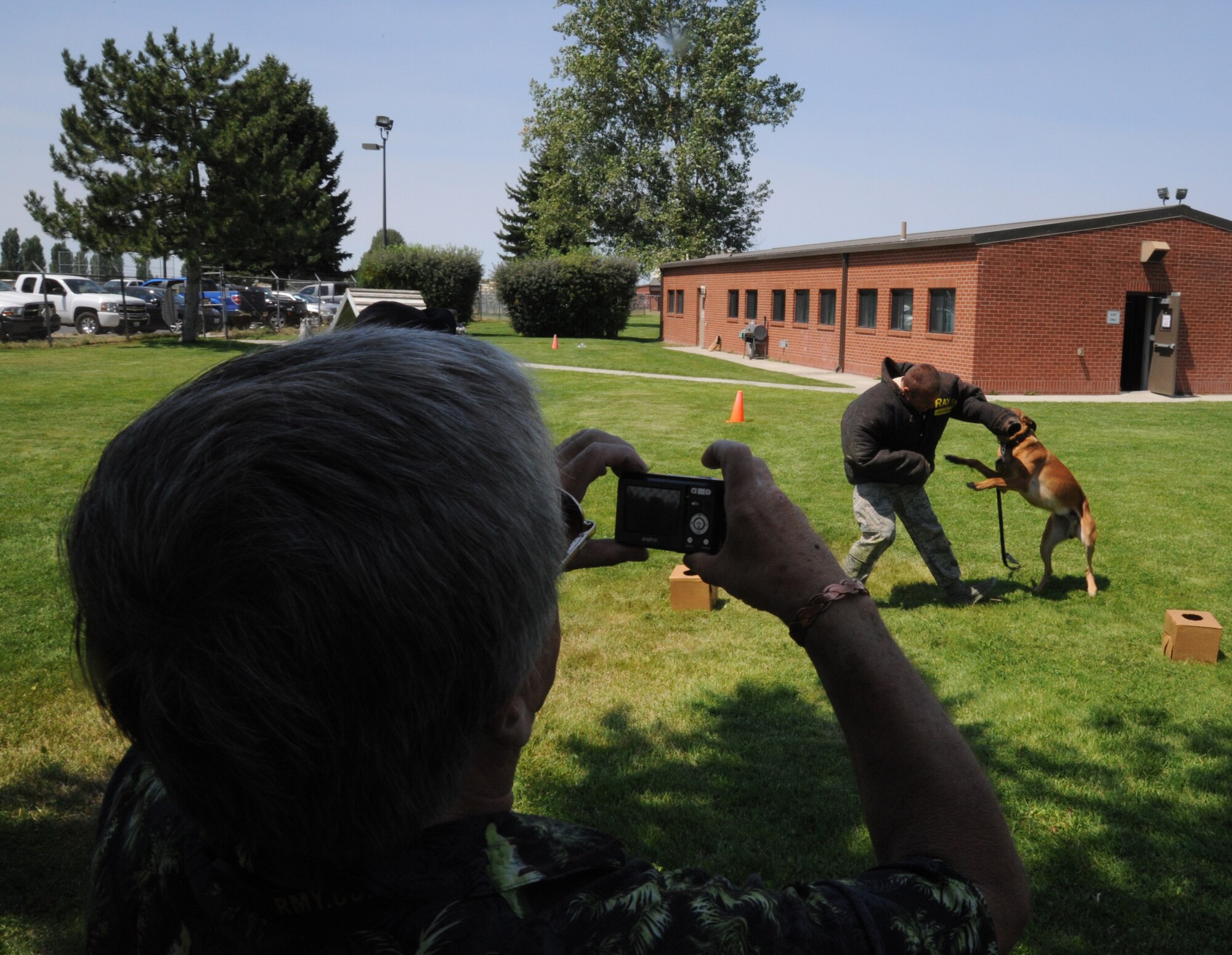 A visitor from the Post Falls, Idaho, Chamber of Commerce takes a photo of Uutah, 92nd Security Forces Squadron military working dog, attacking one of his handlers during a demonstration at Fairchild Air Force Base, Wash., July 26, 2013.  The Post Falls Chamber of Commerce visited the base to experience firsthand the operations of the largest employer in Eastern Washington.  (U.S. Air Force photo by Airman 1st Class Sam Fogleman/Released)