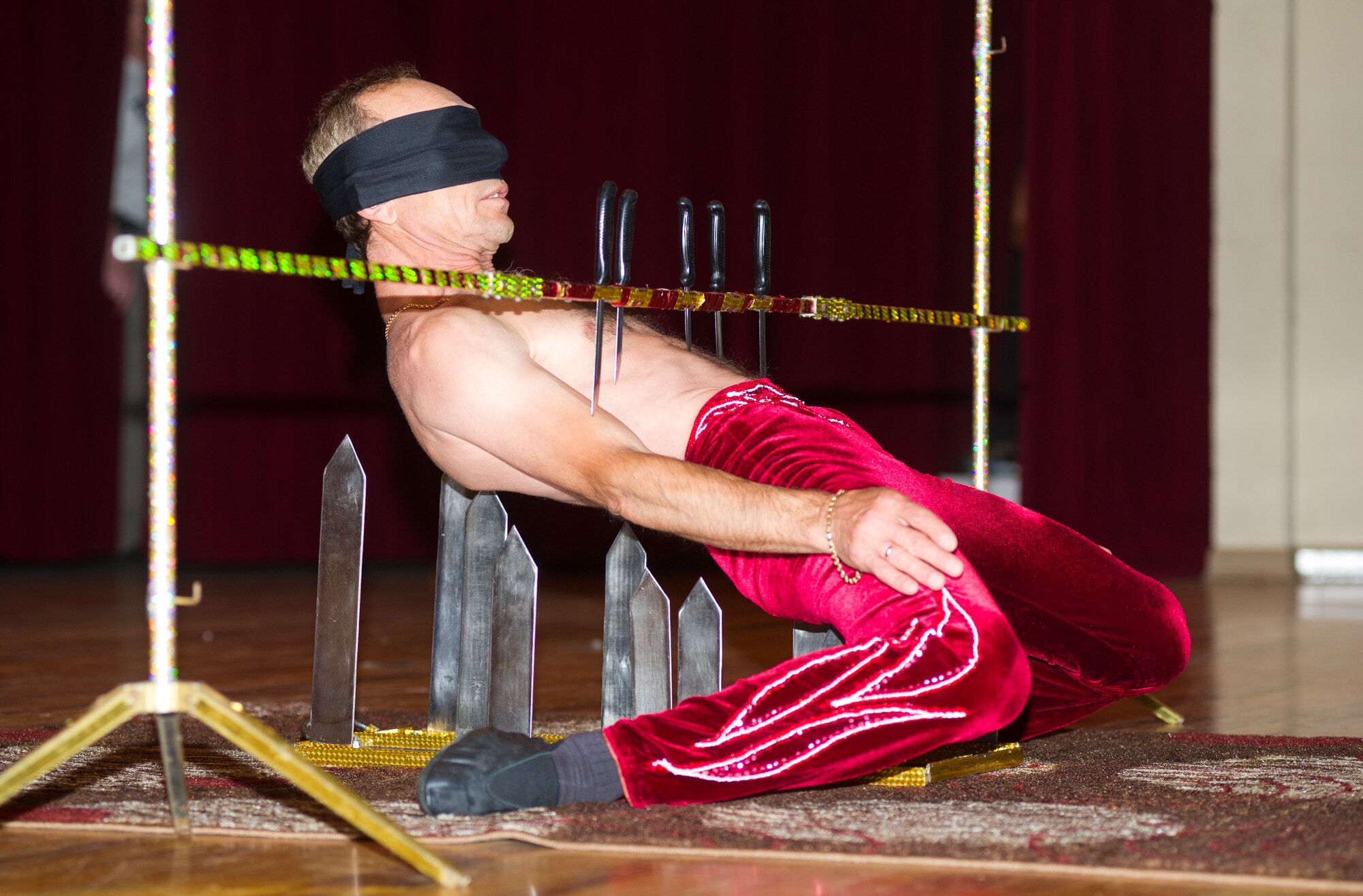 A Funambula performer bends backward to negotiate a knife-laden limbo pole during a military appreciation performance, July 27, 2013, at Welch Theater, Keesler Air Force Base, Miss. Funambula is a theatrical circus act including many acrobatic acts as well as contortionists. (U.S. Air Force photo by Adam Bond)
