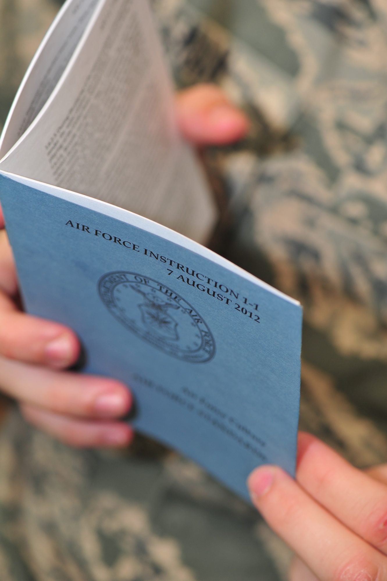 An Airman reads AFI 1-1 at Fairchild Air Force Base, Wash., July 30, 2013.  The pocket-sized blue booklet contains many standards for how Airmen are to conduct themselves.  (U.S. Air Force photo by Senior Airman Taylor Curry/Released)