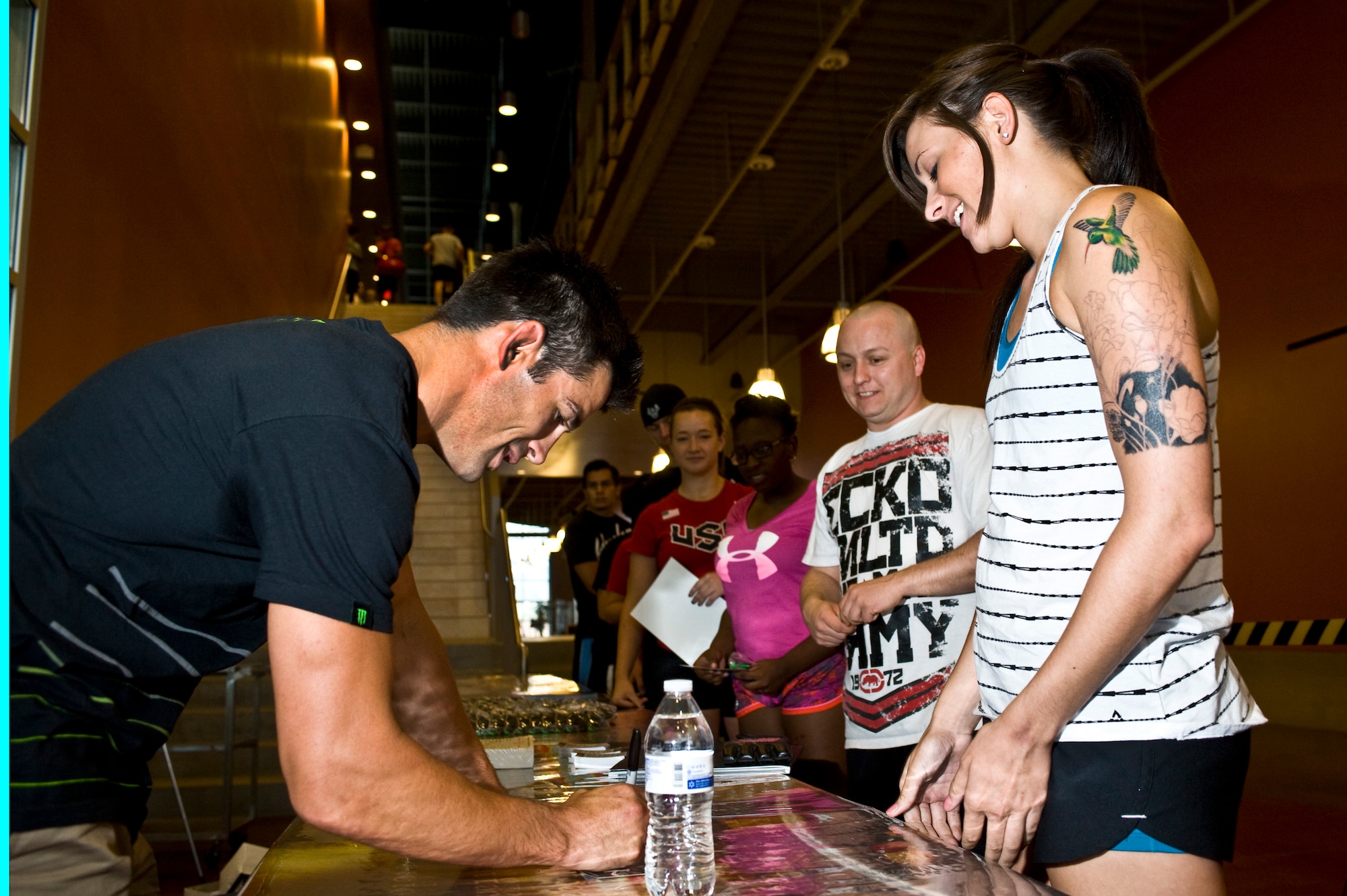 Dominick Cruz, Ultimate Fighting Championship bantamweight champion, signs an autograph for Airman 1st Class Laura Hilborne, 99th Force Support Squadron force management technician, at the Warrior Fitness Center July 25, 2013, at Nellis Air Force Base, Nev. Cruz signed autographs and answered questions from fans during his visit to Nellis AFB. The event was sponsored by the Air Force Reserve Palace Chase and Palace Front Program in order to give active-duty Airmen more awareness about the reserves. (U.S. Air Force photo by Airman 1st Class Christopher Tam)
