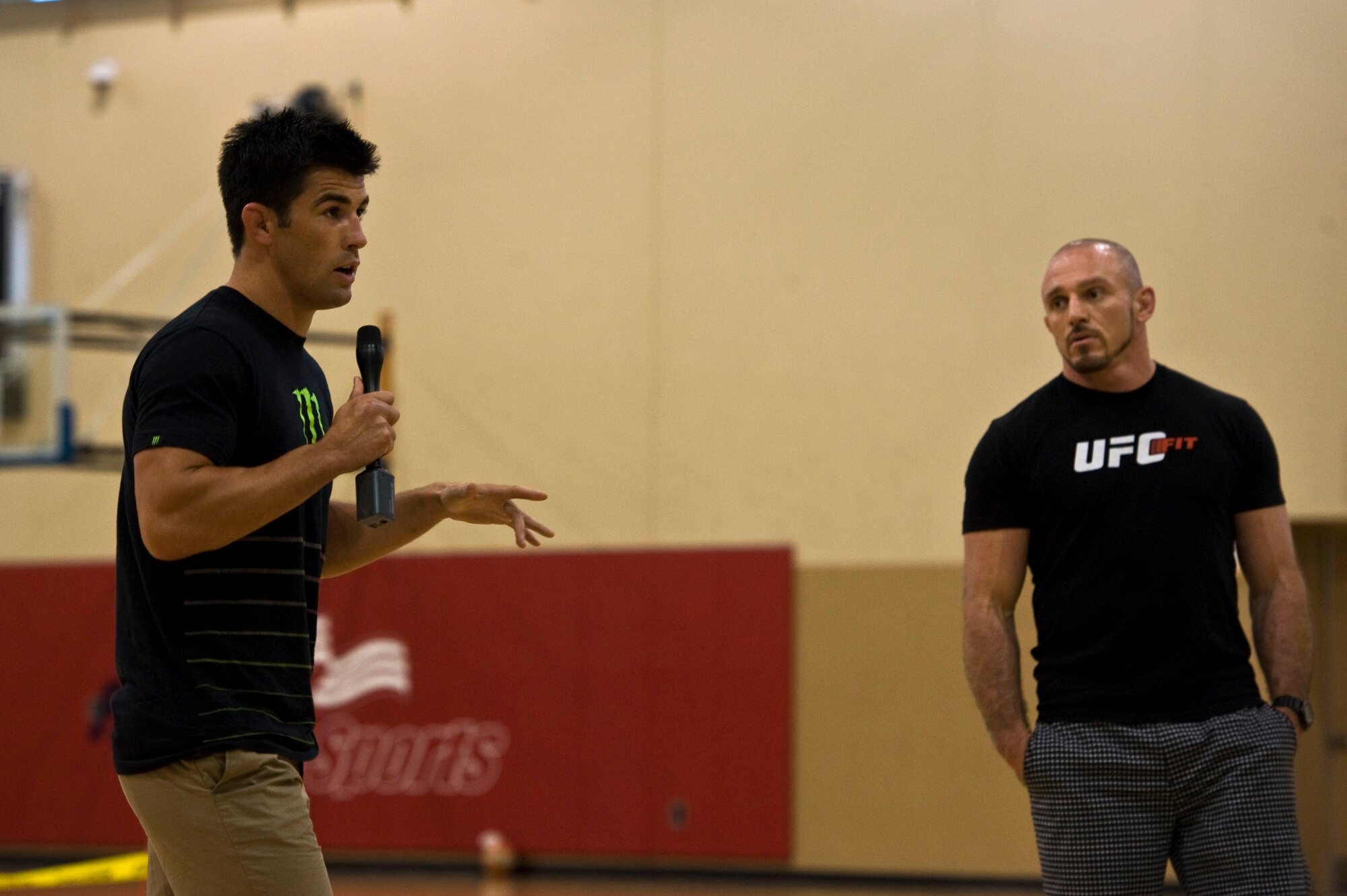 Dominick Cruz (left), Ultimate Fighting Championship bantamweight champion, and Mike Dolce (right), UFC fit coach, speak to military members and civilians at the Warrior Fitness Center July 25, 2013, at Nellis Air Force Base, Nev. Every year the Air Force Reserve Palace Chase and Palace Front Program sponsor UFC fighters to visit the base to make active-duty Airmen more aware of the reserve programs. (U.S. Air Force photo by Airman 1st Class Christopher Tam)