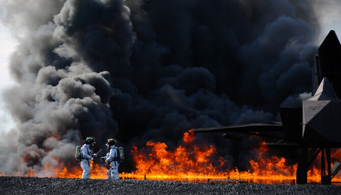Two Airmen from Mountain Home Air Force Base, Idaho light a fire July 25, 2013, near a practice aircraft as part of a Major Accident Response Exercise. The base conducts a MARE as needed to ensure situational readiness of different agencies. (U.S. Air Force photo by Senior Airman Benjamin Sutton/Released)