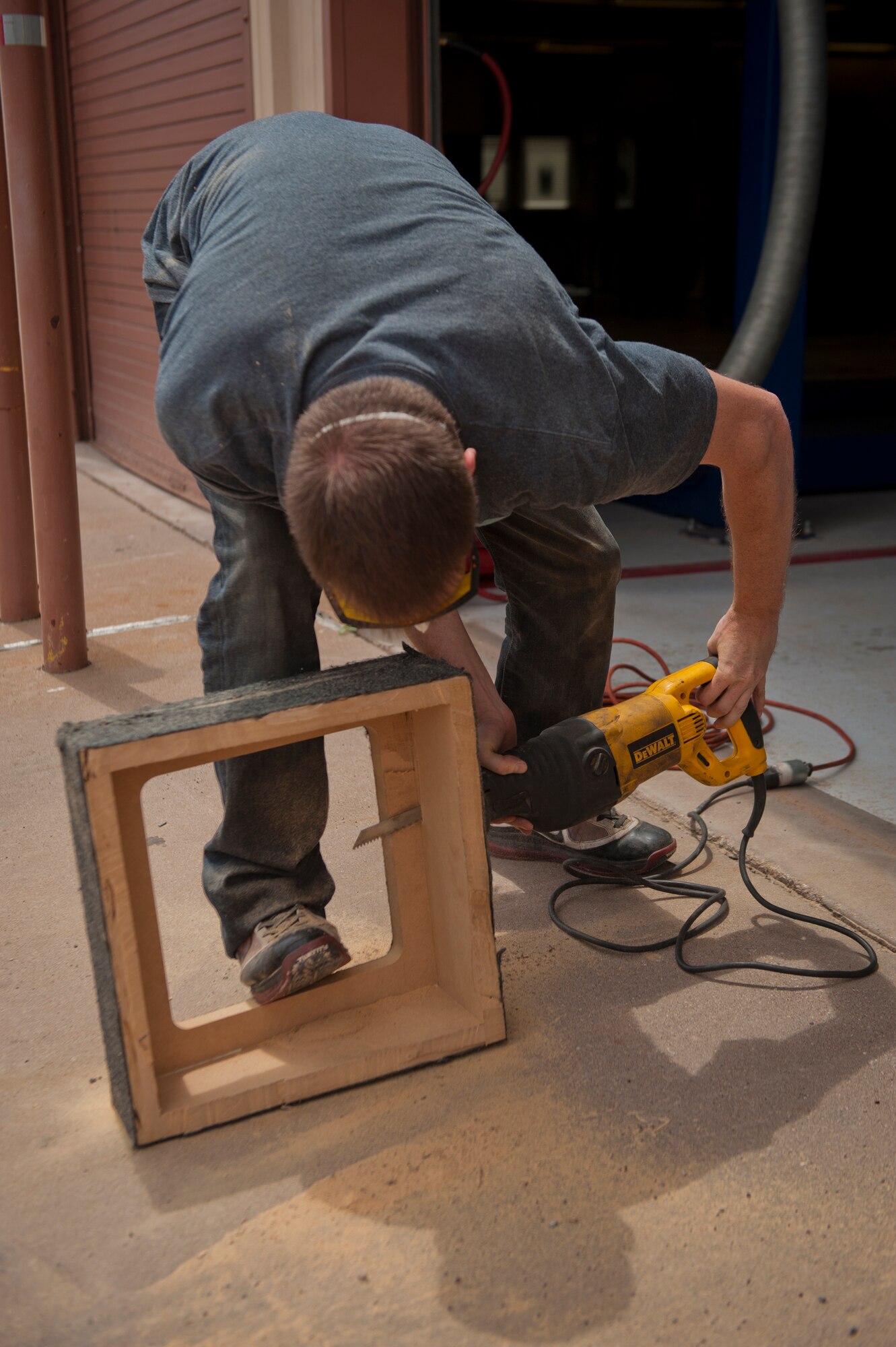 Staff Sgt. William, 6th Reconnaissance Squadron sensor operator instructor, saws excess wood off of a speaker enclosure at the Auto Hobby Shop at Holloman Air Force Base, N.M., July 25. The Auto Hobby Shop provides professional tools and setting that Airmen can use to save money by performing maintenance on their own vehicles. According to current Air Force guidance, the last name of RPA pilots and sensor operators are not releasable due to operational security constraints. (U.S. Air Force photo by Airman 1st Class Aaron Montoya/Released)