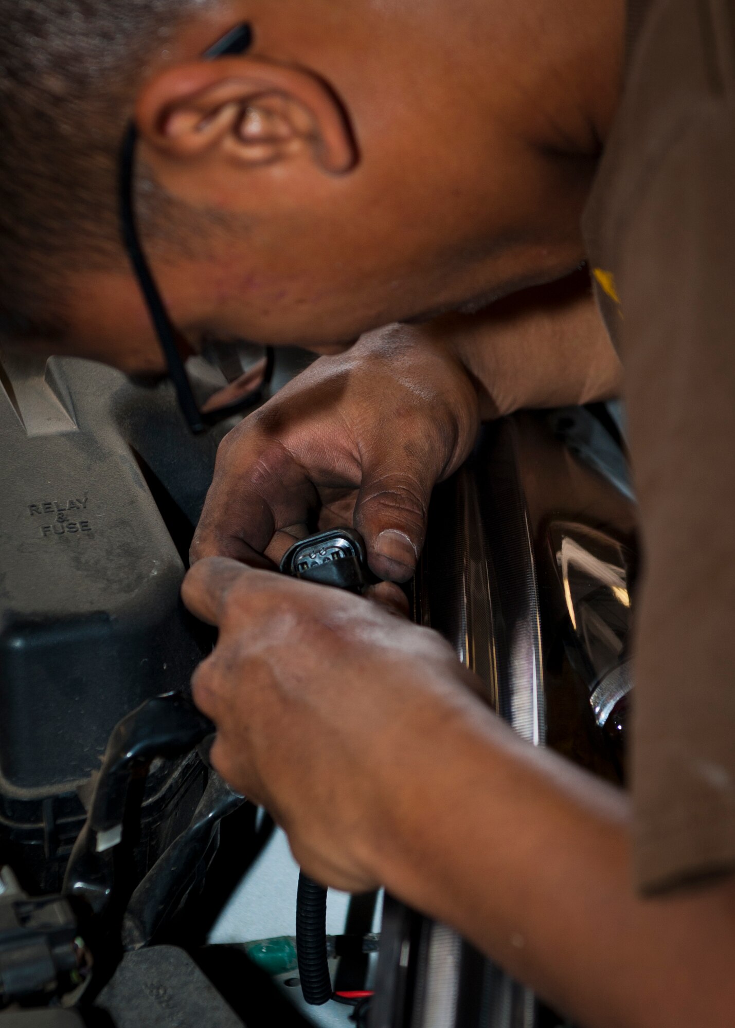 Airman 1st Class Vergel Matheny, 49th Aircraft Maintenance Squadron avionics technician, plugs in a newly-installed headlight unit on his vehicle at the Auto Hobby Shop at Holloman Air Force Base, N.M., July 25. The Auto Hobby Shop provides a safe and professional setting where Airmen can save money by performing maintenance on their own vehicles. (U.S. Air Force photo by Airman 1st Class Aaron Montoya/Released)