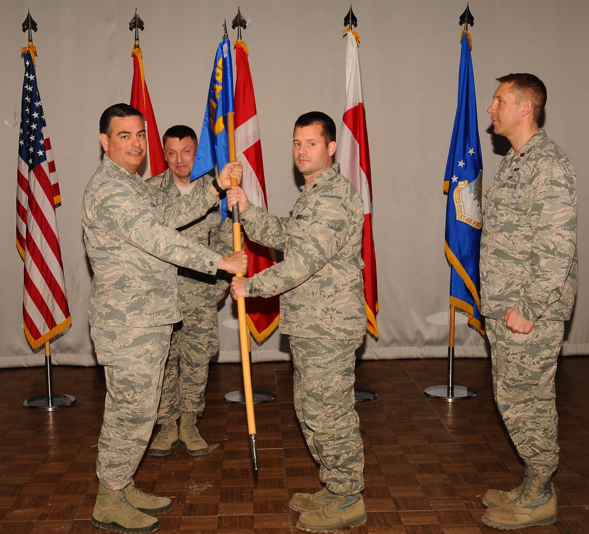 THULE AIR BASE, Greenland – Col. Mike Colón (left), former 821st Air Base Group commander, passes the 821st Support Squadron guidon to Maj. Jeremiah Hammill, during a change of command ceremony. Hammill took command of the 821st SPTS June 27. The 821st SPTS is one of the 21st Space Wing’s 23 geographically separated units, and supports Thule’s missile warning, missile defense, space surveillance and satellite command and control missions through engineering, communications, medical, logistical, air field, services and personnel support. Hammill replaced outgoing commander Maj. Kevin Golart. (U.S. Air Force photo)