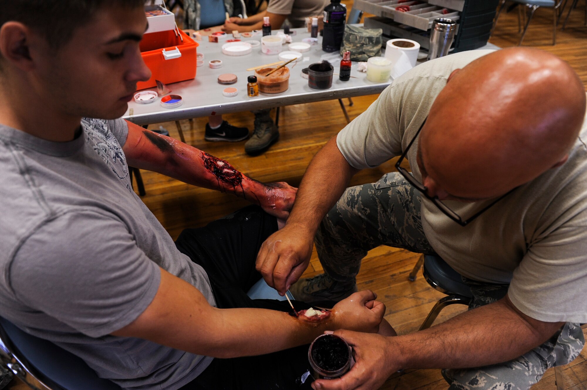 Master Sgt. Christopher Woar, a 19th Aerospace Medical Dentist Squadron chief of flight and operation medicine  glues on a simulated fractured wrist to moulage victim Airman 1st Class Steven Hamilton, a 19th Component Maintenance Squadron fuel systems repairer July 24, 2013, at Little Rock Air Force Base, Ark. The purpose of the Major Accident Response Exercise was to test the response of the bases and the city of Jacksonville’s first responders. (U.S. Air Force photo by Airman 1st Class Cliffton Dolezal)