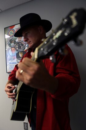 Lt. Col. Jerard A. Brewer, Marine Corps Installations-East Marine For Life officer in charge, plays his guitar next to a GI Jams poster featuring eight artists including himself aboard Marine Corps Base Camp Lejeune, July 26. Brewer, a songwriter, has four albums worth of songs on the website alone that are performed by various vocalists and musicians.