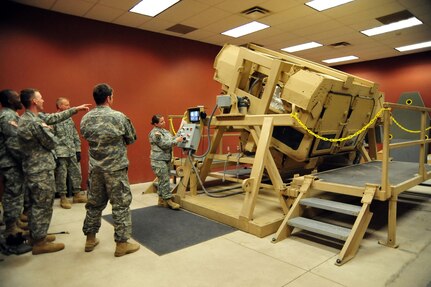 Soldiers assigned to Headquarters and Headquarters Battery, 3rd Battalion, 157th Field Artillery, Colorado Army National Guard, watch as four of their peers experience the Humvee Egress Assistance Trainer at Fort Carson in Colorado Springs, Colo., Feb. 20, 2009.