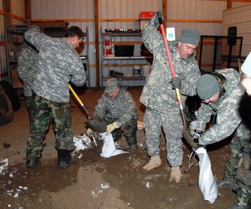 North Dakota National Guard Soldiers fill sandbags in garage opened by the city of Linton, N.D., in back of the courthouse. The sand was pushed inside, and now the Soldiers are sandbagging out of the snow and 14 degree windchill.