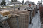 Spc. Joshua Klundt, of the 817th Engineer Company (Sappers), pulls one end of a collapsible barrier device called a HESCO March 24 in Fargo, N.D. The sections of HESCO are being linked together and filled with sand to create a flood barrier from the rising waters of the Red River. 