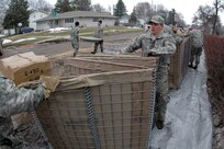 Spc. Joshua Klundt, of the 817th Engineer Company (Sappers), pulls one end of a collapsible barrier device called a HESCO March 24 in Fargo, N.D. The sections of HESCO are being linked together and filled with sand to create a flood barrier from the rising waters of the Red River. 