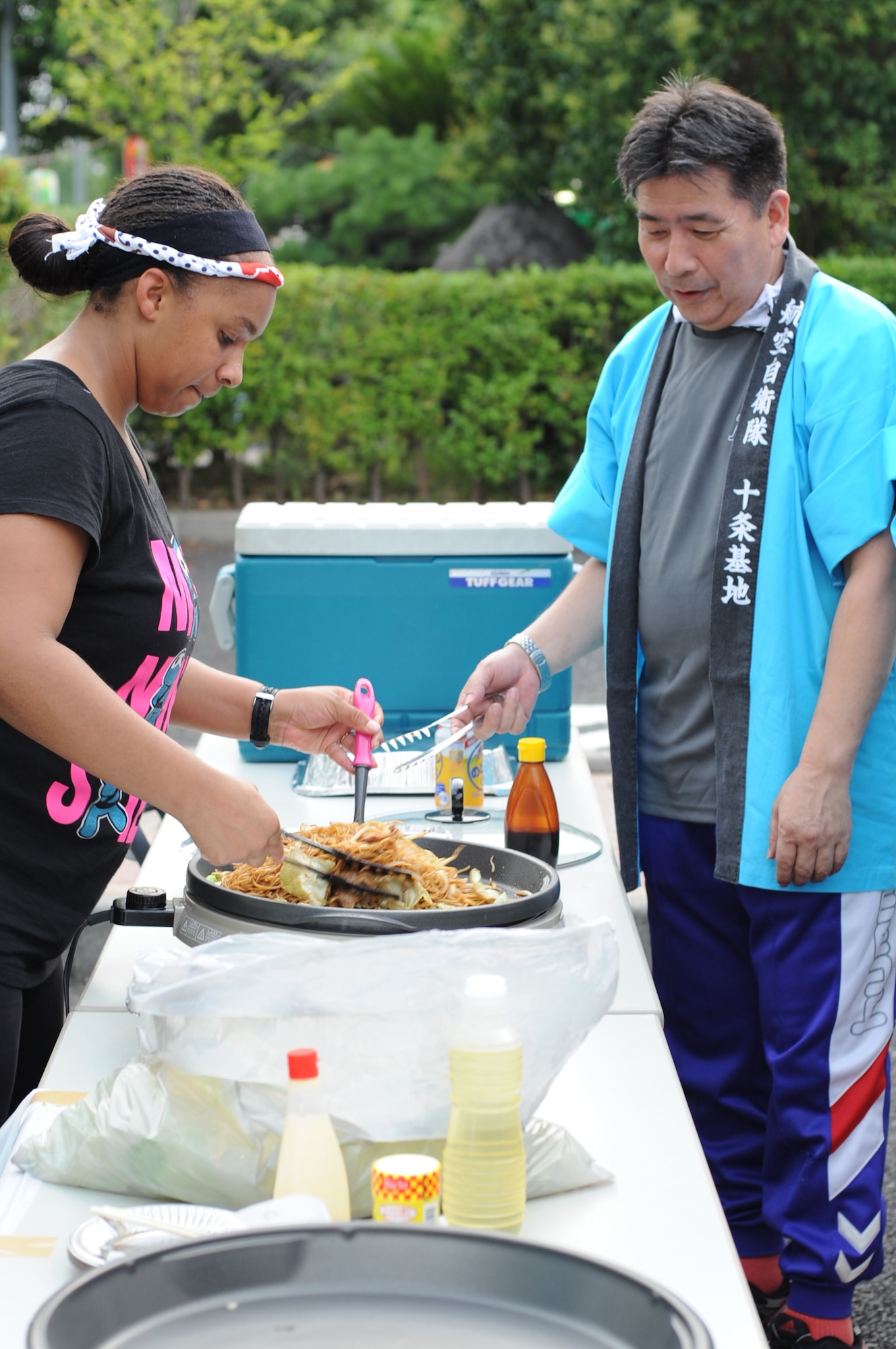 JUJO AIR STATION, Japan -- Staff Sgt. Kassie Posas, 374th Operations Group, makes yakisoba with Warrant Officer Yoshiyuki Miyata, Japan Air Self-Defense Force 2nd Department of Air Materiel Command senior enlisted advisor, July 26, 2013, at Jujo Air Base, Japan. Posas and other members from Yokota Air Base, Japan, participated in a cultural exchange with JASDF at Jujo Air Base, Japan. (U.S. Air Force photo by Senior Airman Desiree Economides)