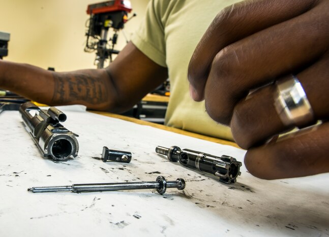 Staff Sgt. Julius Taylor, 628th Security Forces Squadron Combat Arms Training and Maintenance instructor, inspects the bolt carrier and bolt cam to include the firing and cam pin of an M-4 carbine rifle July 30, 2013, at Joint Base Charleston – Air Base, S.C. CATM instructors are subject matter experts on operating, disassembling and maintaining all weapons held in the armory. (U.S. Air Force photo/ Senior Airman Dennis Sloan)