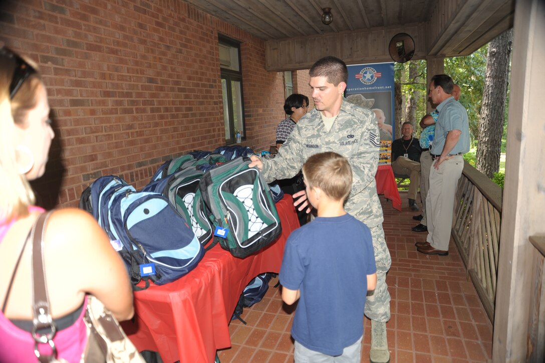 Tech. Sgt. Ronald Megginson, Airman & Family Readiness Center NCO, shows Chandler Loveland the different backpacks and tells him about the winning ticket that may be inside during the Operation Homefront 2013 Back-To-School Brigade program distribution July 25. Megginson and other volunteers handed out 200 backpacks filled with back-to-school supplies as part of a partnership between the A&FRC, Operation Homefront and various corporate and private sponsors nationwide. Items donated for the campaign include spiral notebooks, pens, pencils, markers, crayons, notebook paper, rulers, colored pencils, calculators, and erasers. This program saves military families a major education expense, especially for those experiencing financial hardships. (U.S. Air Force photo by Raymond Crayton)