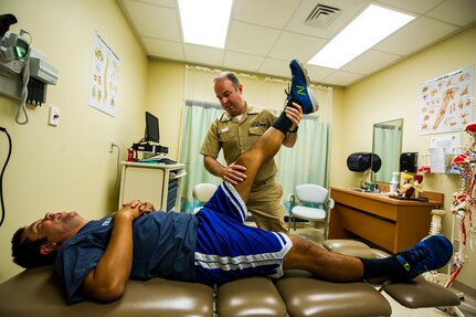 Navy Lt. Gregory Norris, Naval Health Clinic Charleston physical therapist, maneuvers Coast Guard Petty Officer 1st Class Dan Coen’s leg during a physical therapy appointment July 29, 2013 at Joint Base Charleston – Weapons Station, Goose Creek, S.C.  NHCC provides quality healthcare services for approximately 12,000 beneficiaries throughout the LowCountry, including a sick call clinic for Sailors assigned to the Weapons Station. (U.S. Air Force photo/ Senior Airman George Goslin)