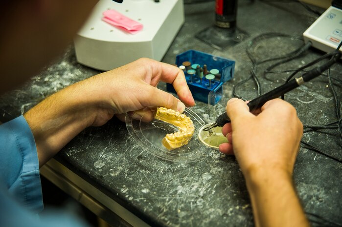 Navy Lt. Clay Miller, Naval Health Clinic Charleston dental officer, makes a temporary partial denture using a Therma-Knife July 29, 2013, at Joint Base Charleston - Weapons Station, Goose Creek, S.C. The Therma-Knife produces clean cuts through plastic fiber of all types and diameters as an alternative to polishing or cutting. (U.S. Air Force photo/ Senior Airman George Goslin)