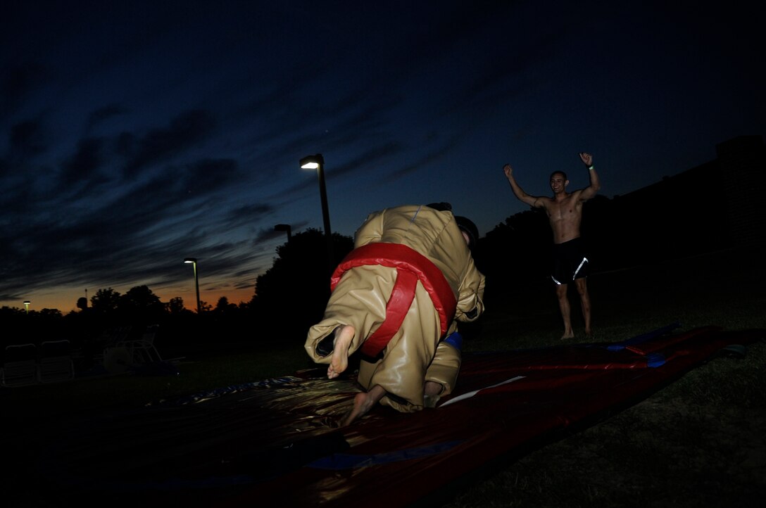 Airmen 1st Class Scott Peyton, 11th Civil Engineering Squadron engineering assistant cheers on airmen as they wrestle in sumo suits during Airmen Summer Pool Block Party at Joint Base Andrews, Md., July 26, 2013. Airmen Committed to Excellence, a private organization dedicated to the morale and well-being of enlisted Airmen E-1 through E-4 sponsored, the event. (U.S. Air Force photo/ Airman 1st Class Nesha Humes)