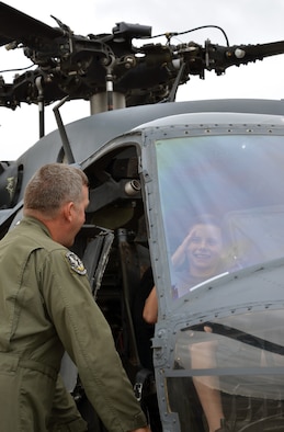 Chief Master Sgt. Mike Flake, 943rd Rescue Group, Davis-Monthan Air Force Base, Ariz., explains rescue operations to a young visitor sitting in an HH-60G Pave Hawk helicopter during the 304th Rescue Squadron reunion picnic at Portland International Airport, Ore., July 28, 2013. The 304th Rescue Squadron and 943rd Rescue Group are geographically separated units of the 920th Rescue Wing, Patrick Air Force Base, Fla.  (U.S. Air Force photo/Tech. Sgt. Anna-Marie Wyant)