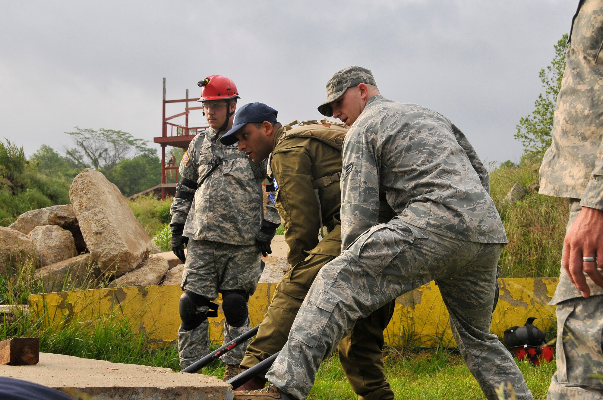 Air Force Senior Airman Cody W. Eslick, 181st Intelligence Wing, 19th CERFP, along with an Israeli soldier, use a crowbar to lift and move heavy slabs of concrete at Camp Atterbury, Edinburgh, Ind., June 10, 2013. The training conducted at Camp Atterbury involved Air and Army Guardsmen, Bloomington Fire Department and Israelis Search and Rescue team in an exercise called United Front II. (U.S. Air National Guard photo by Senior Master Sgt. John S. Chapman/Released)
