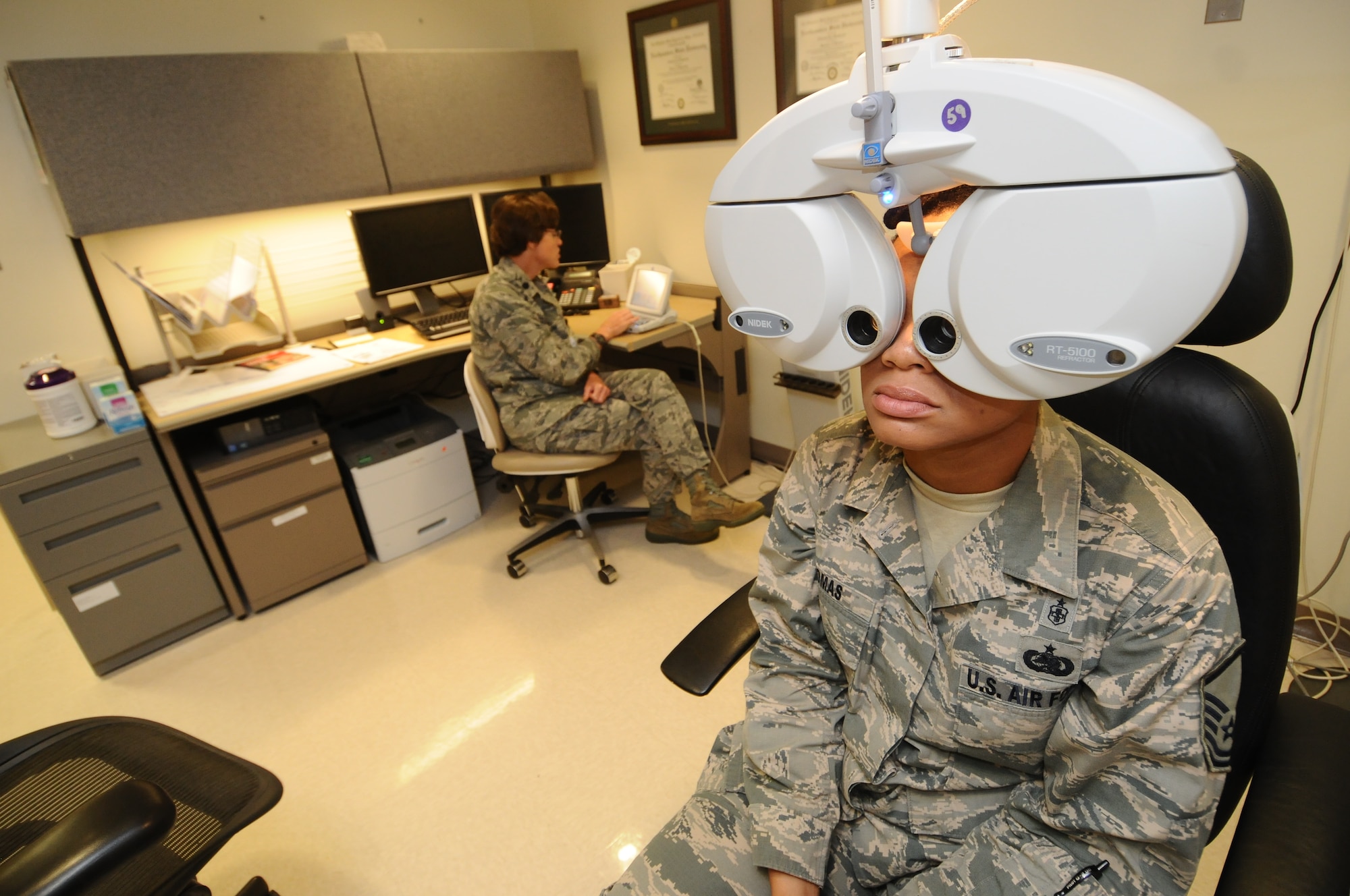Master Sgt. Tamika Thomas, 36th Medical Operations Squadron aerospace medicine flight chief, tests different lenses to find the correct eyeglasses prescription controlled by Lt. Col. Christine Stabile, 36th Medical Support Squadron commander, July 31, 2013, on Andersen Air Force Base, Guam. The new system allows the series of machines that are used in eye exams to synchronize electronically for a faster flow of data.  (U.S. Air Force photo by Airman 1st Class Emily A. Bradley/Released)