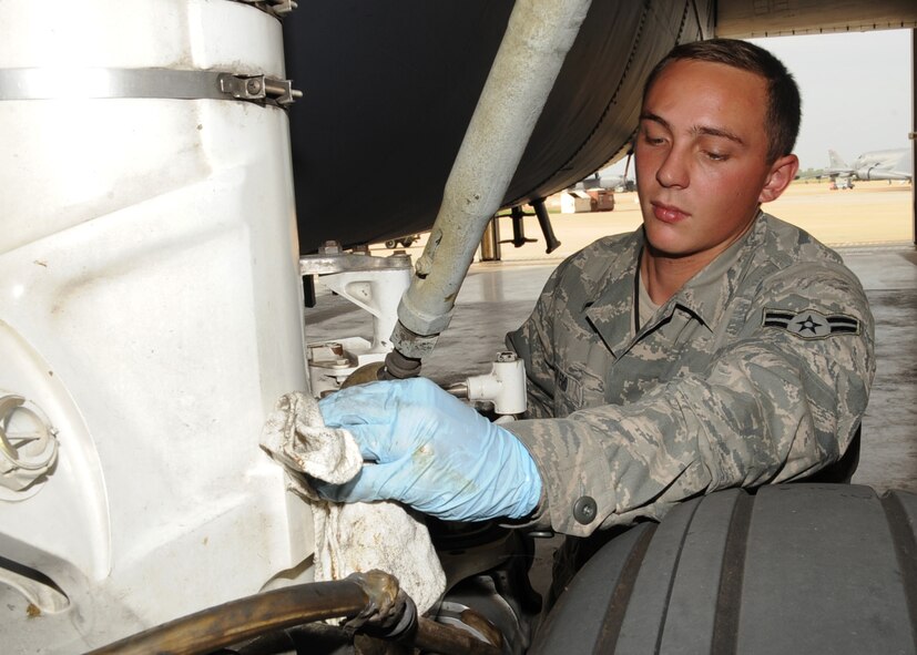 Airman 1st Class Joshua Otero, 96th Aircraft Maintenance Unit crew chief, cleans excess lubricant from the landing gear of a B-52H Stratofortress on Barksdale Air Force Base, La., July 30, 2013. Otero was a part of the crew that prepped Col. Andrew Gebara's, 2nd Bomb Wing commander, B-52H Stratofortress for flight July 29. Otero was barely a week old when Gebara took his first flight exactly 20 years ago. (U.S. Air Force photo/Senior Airman Sean Martin)
