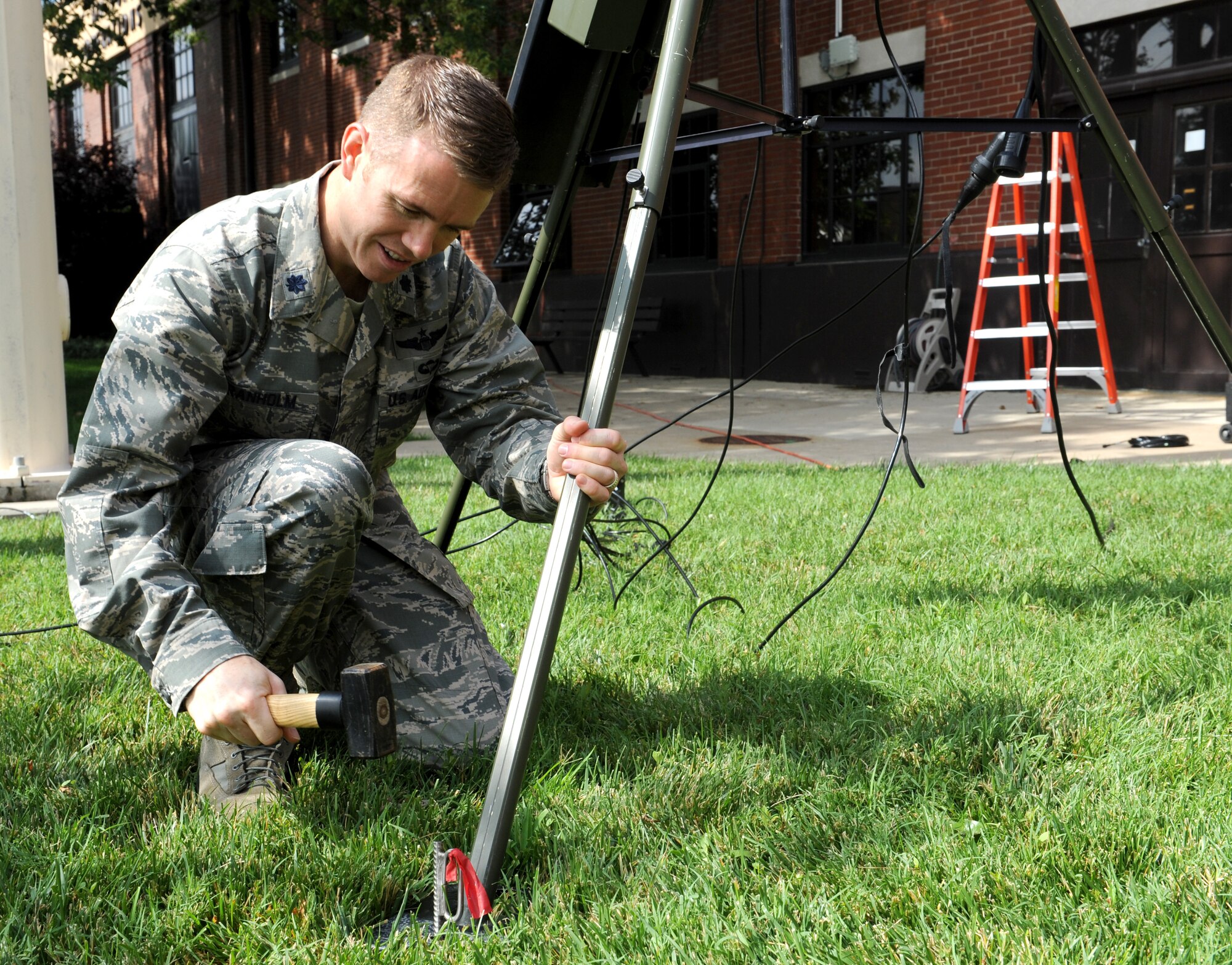 Lt. Col. George Granholm, 375th Operations Support Squadron commander, secures the base of the TMQ-53 July 22 on base.  The TMQ-53 is a self-contained, deployable unit that provides measurements of wind speed, wind direction, gust, temperature, relative humidity, pressure, cloud ceiling heights, visibility, present weather, precipitation accumulation and lightning detection.  (U.S. Air Force photo/Staff Sgt. Maria Bowman)