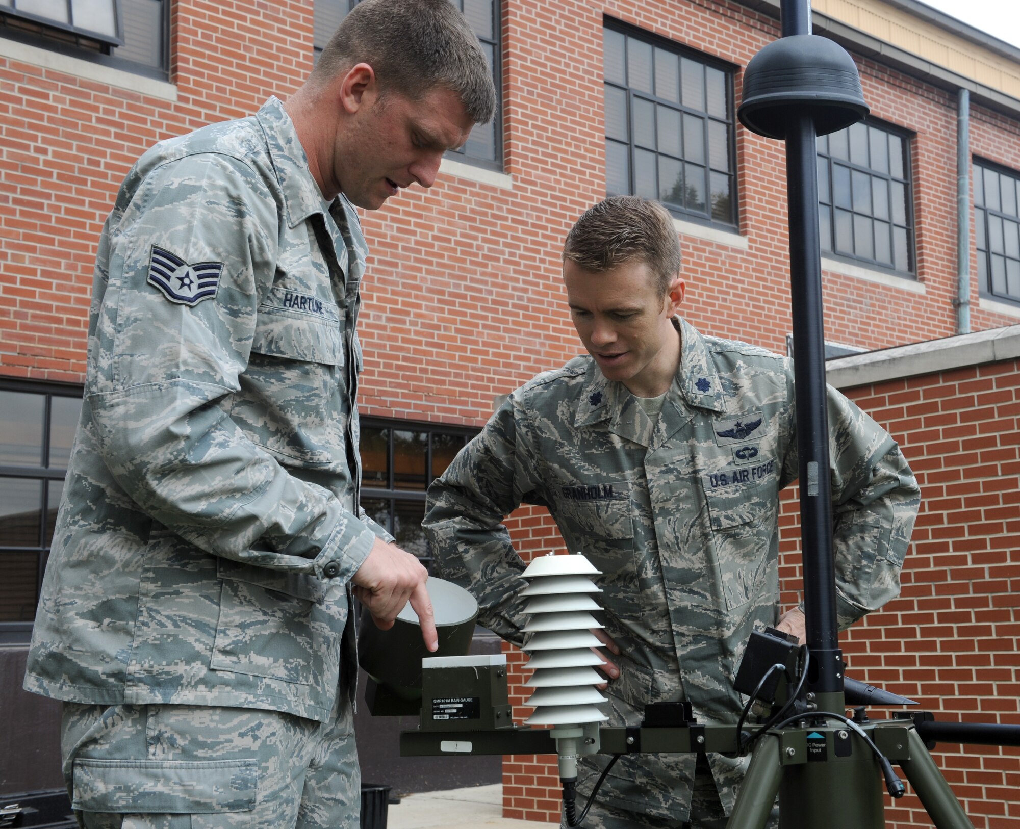 Staff Sgt. Joshua Hartline, 375th Operations Support Squadron weather forecaster, demonstrates how the rain gauge measures the amount of liquid precipitation to Lt. Col. George Granholm, 375th Operations Support Squadron commander.  The rain gauge gathers and measures the amount of liquid precipitation over a period of time.  To get an accurate reading, rain gauges should be placed in an open are where there are no obstacles to block the rain.  (U.S. Air Force photo/Staff Sgt. Maria Bowman)