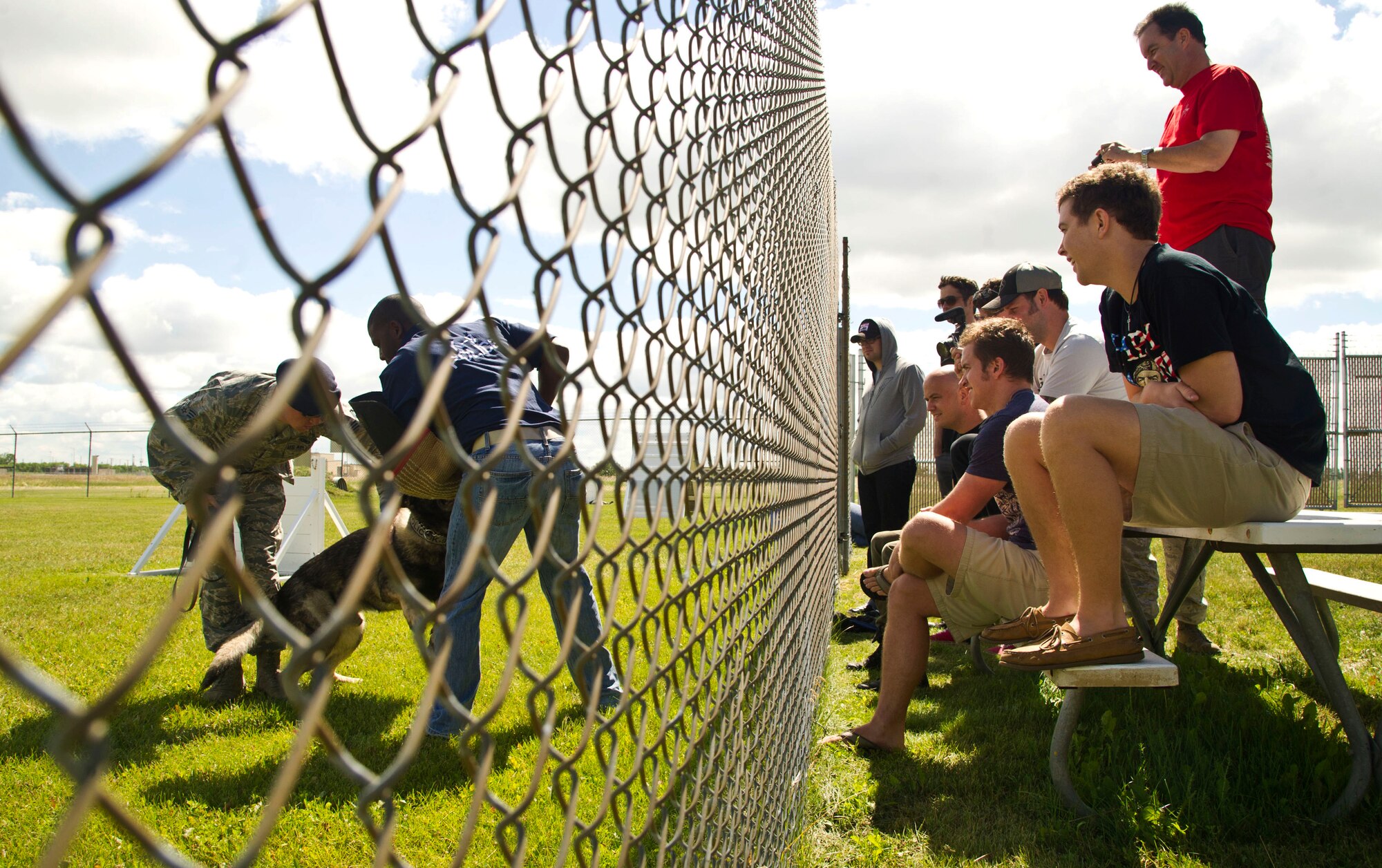 Amerian country singer Scotty McCreery and his bandmates watch a military working dog demonstration, July 25. McCreery recieved a base tour the day after his USO concert for Airmen and their families. (U.S. Air Force photo/Senior Airman Brittany Y. Auld)